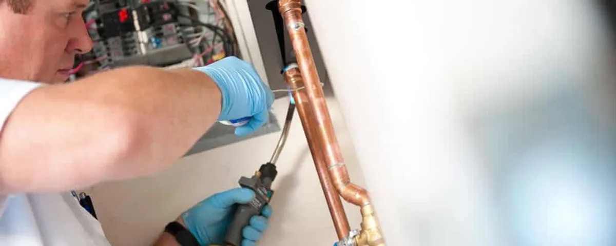 Water heater repair technician testing copper pipe connections and controls in Redding, CA